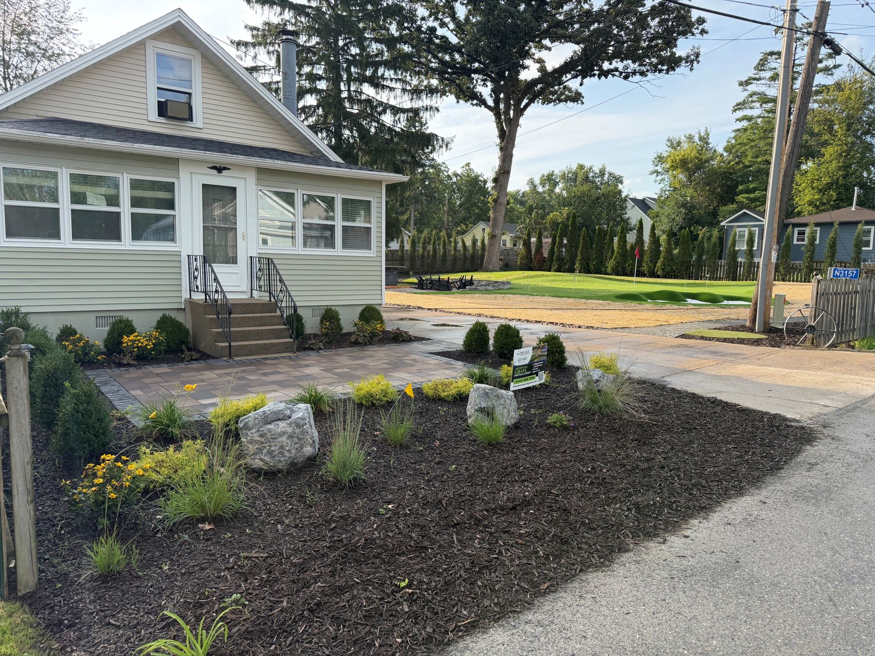 Front of the updated cottage with paver walkway and new landscaping, with the putting green beyond