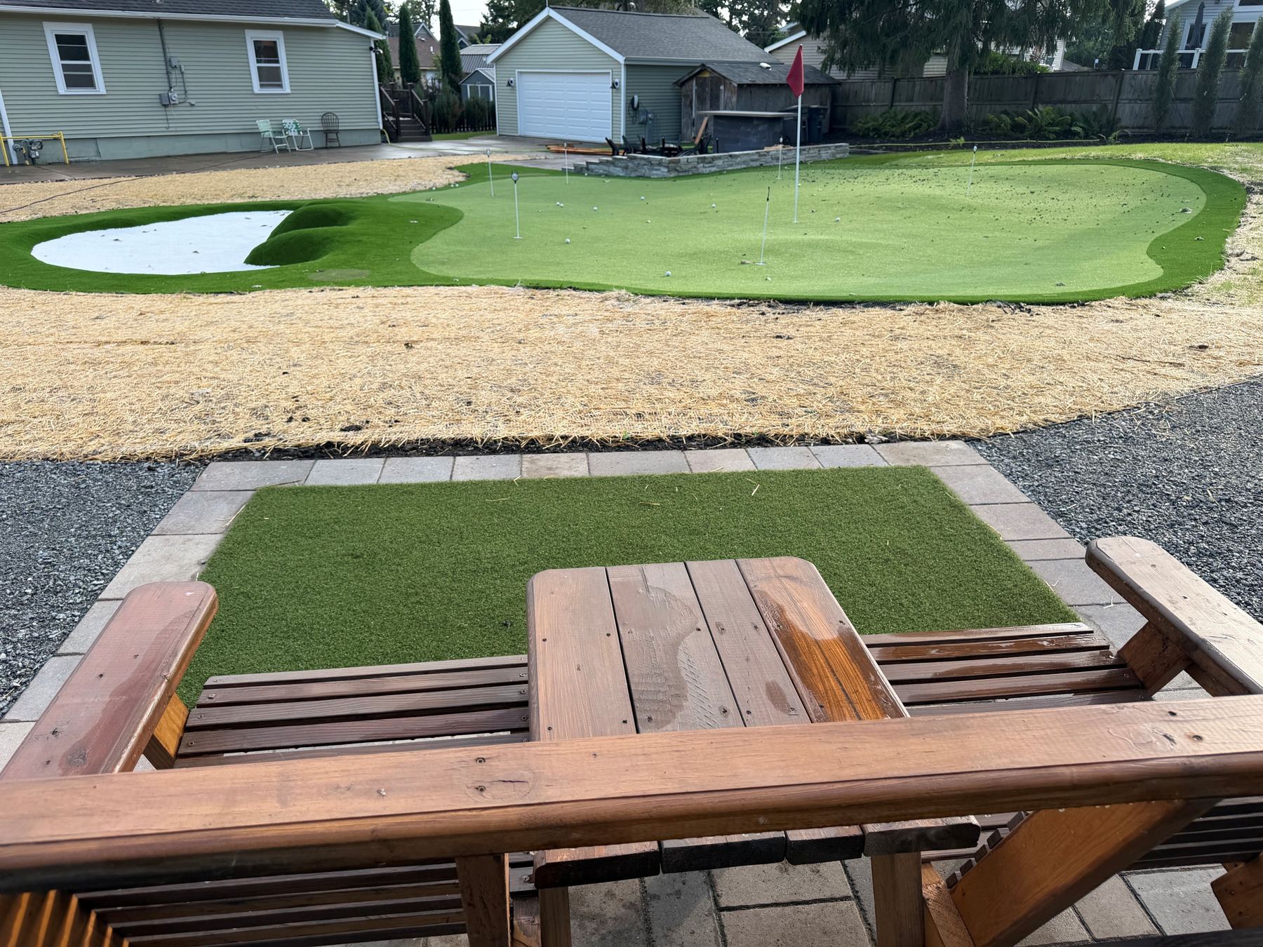 View across the putting green from wooden chairs on the paver deck