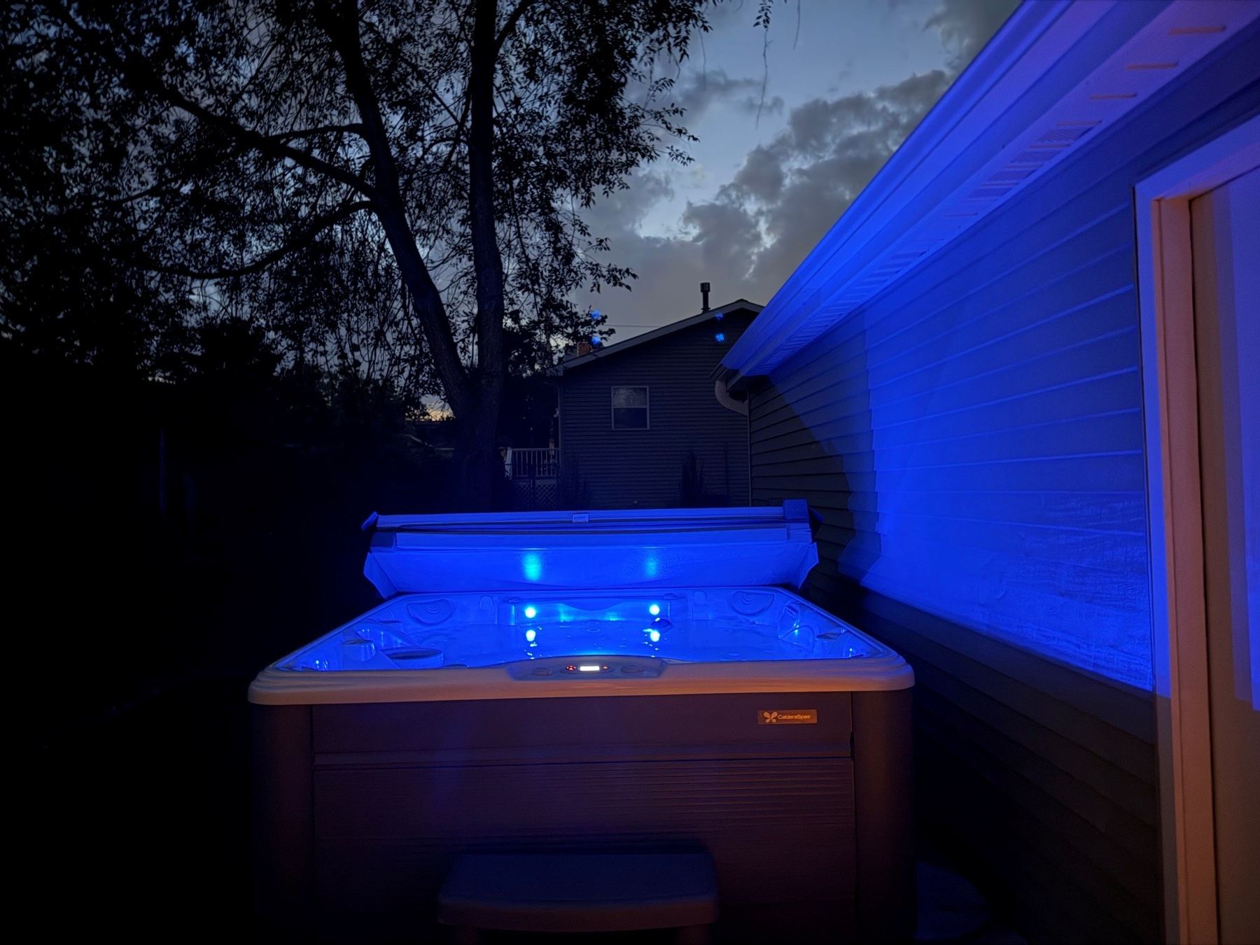 Outdoor hot tub lit blue at night beside the clubhouse
